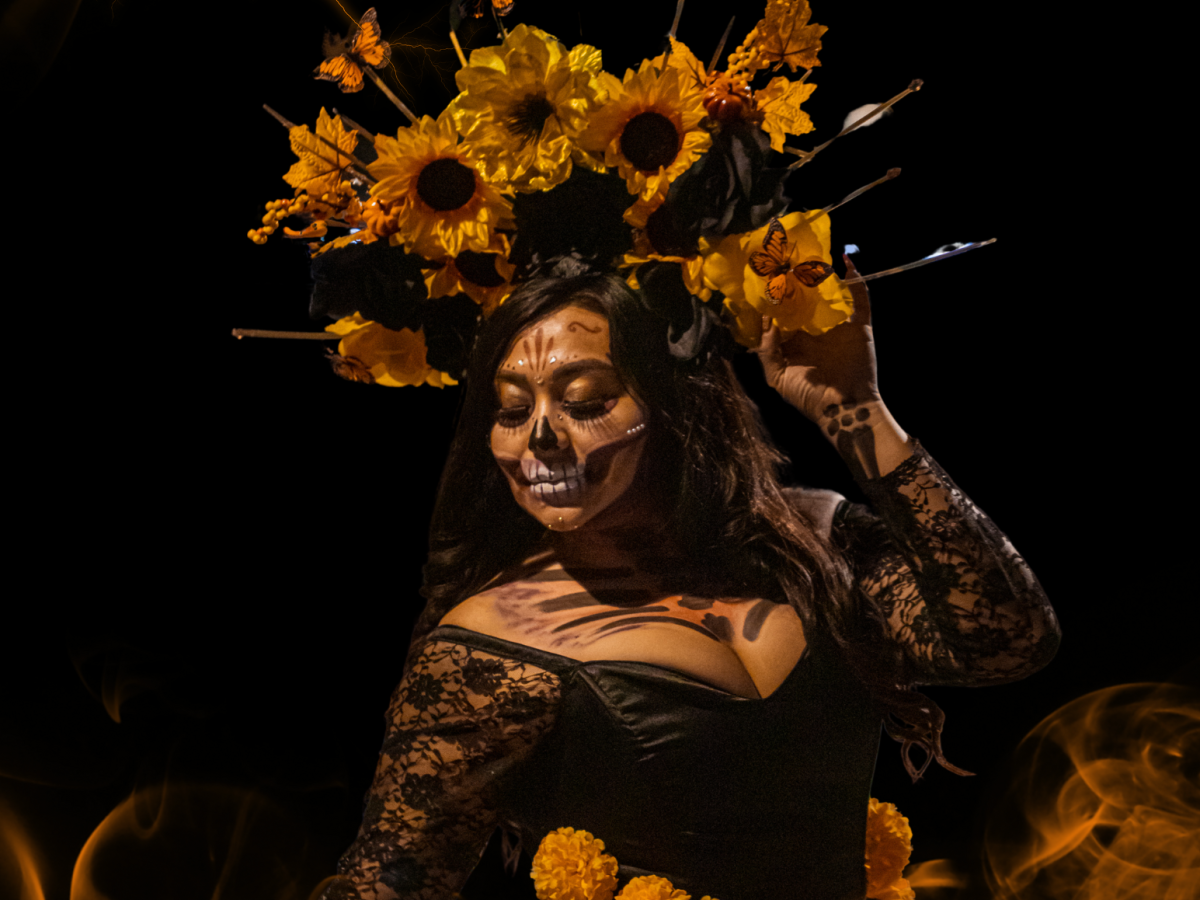 A person adorned with a vibrant floral headdress and face paint, dressed in black lace, surrounded by mystical orange smoke.